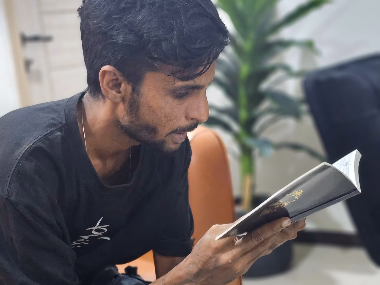 A young believer sitting alone with an open Bible, reading closely.